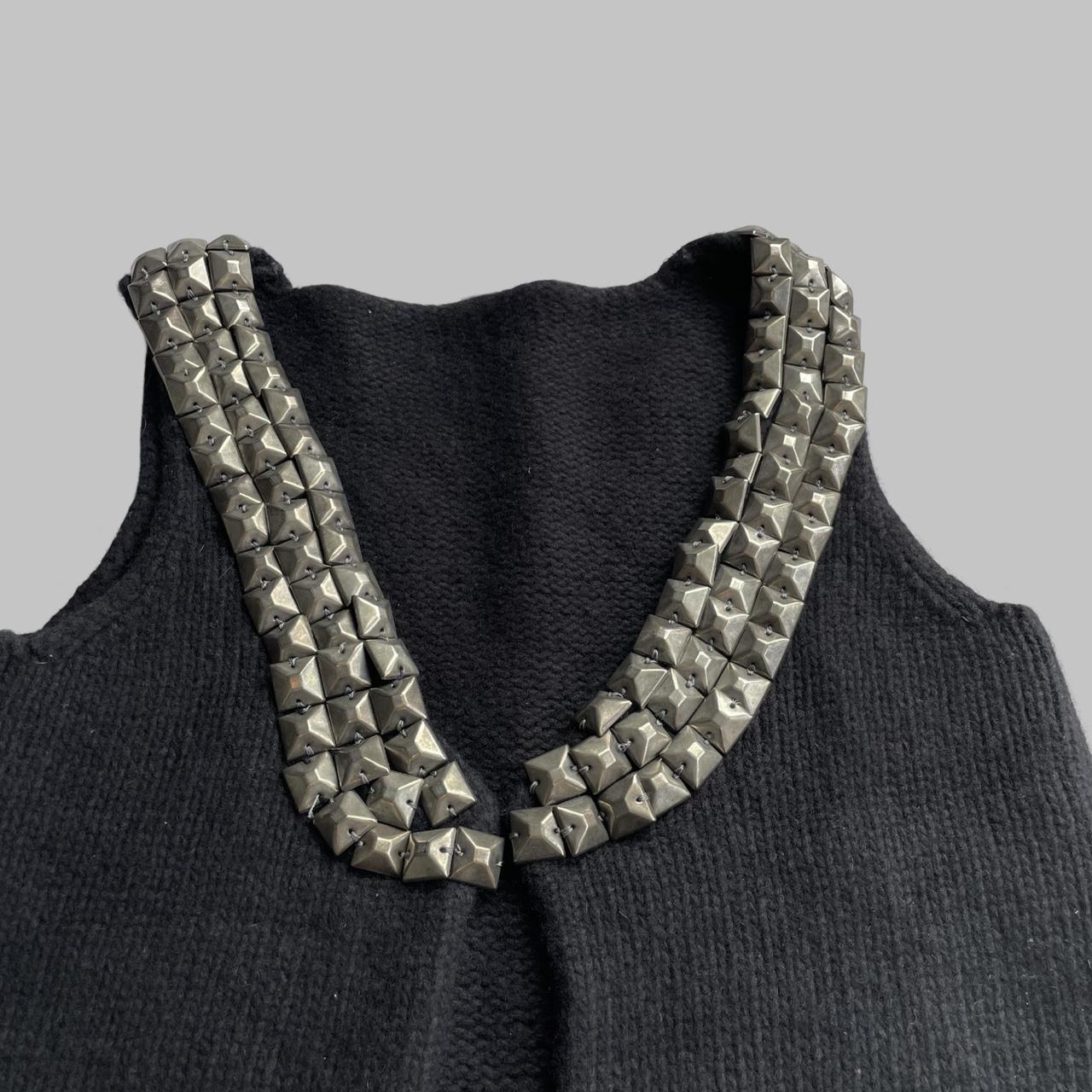Sleeveless knit black vest with silver studs.
